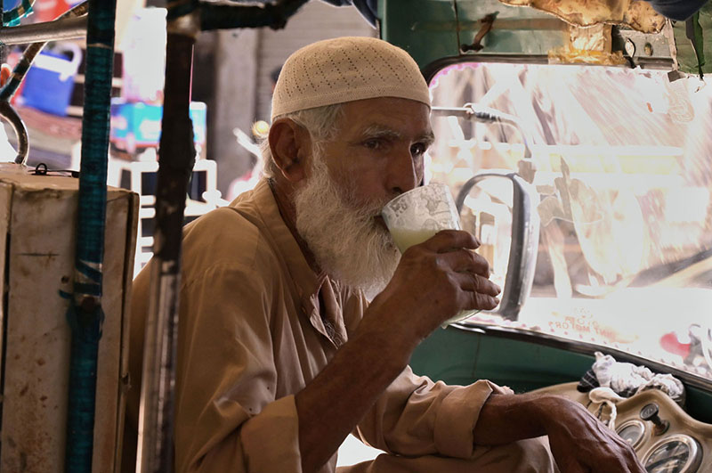 An elder man enjoy drinking traditional dirnk (Lassi) to get relief from hot weather in the city