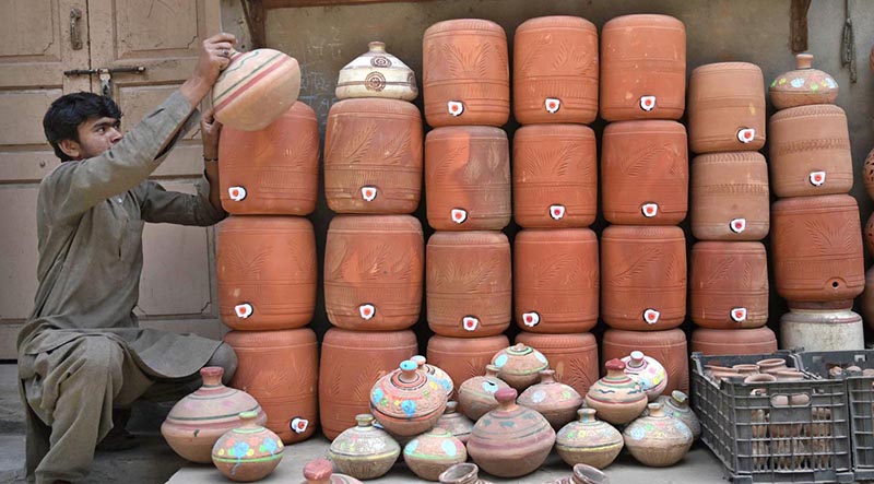 A vendor arranging and displaying clay pots outside his shop at Gwalmandi to attract the customers.
