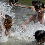Youngsters enjoy bathing in the pond to get some relief from hot weather in the Federal Capital