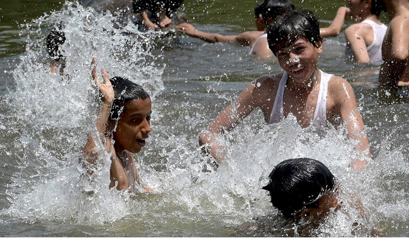 Youngsters enjoy bathing in the pond to get some relief from hot weather in the Federal Capital