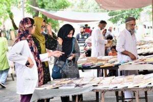 A woman selecting old books from a roadside stall at Mall Road