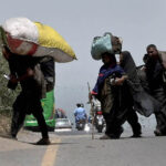 Gypsy family on the way carrying their luggage near expressway in the Federal Capital