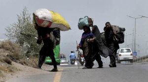 Gypsy family on the way carrying their luggage near expressway in the Federal Capital