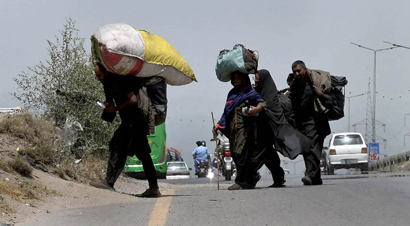 Gypsy family on the way carrying their luggage near expressway in the Federal Capital