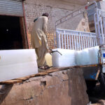 A worker loading ice blocks from an ice making factory to deliver to shops during a hot weather at Tarlai