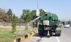 A CDA worker busy in watering plants along Islamabad Expressway.