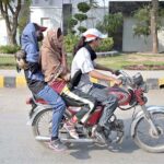 A girl along with other girls on the way on motorcycle at College Road