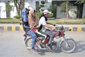 A girl along with other girls on the way on motorcycle at College Road