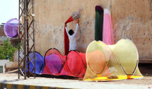 A vendor is busy displaying mosquito nets to attract customers at his roadside setup