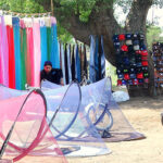 A vendor displays mosquito nets and other items to attract customers at his roadside setup