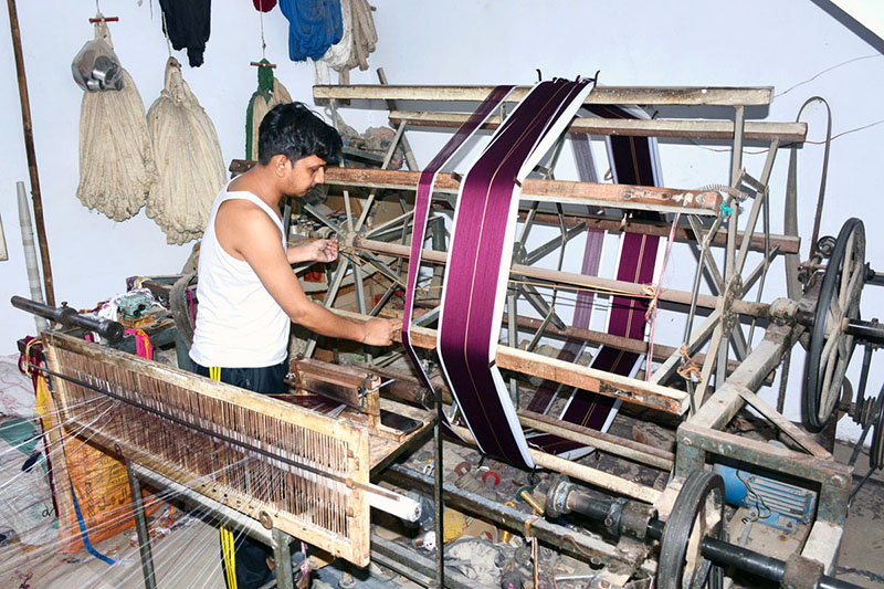A worker busy in preparing cloth on power loom in a local factory.