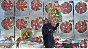 A vendor arranging and displaying room coolers to attract the customers at his setup.