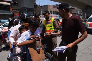 Rescue 1122 workers distributing heat stroke awareness pamphlets and water to a public at Stadium Chowk.