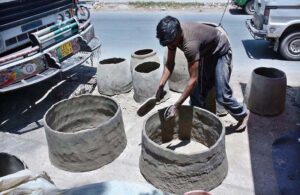 An artisan busy in preparing traditional clay oven (tandoor) at his workplace.