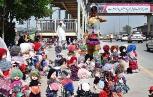 A young vendor displaying colorful dolls to attract the customers at his roadside setup near Gulbahar GT Road.