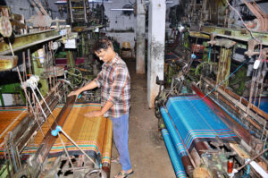 A worker busy in preparing cloth on power loom in a local factory.