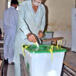 A woman casts her vote at a polling station during by-election in constituency NA-148