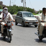 Motorcyclist covers his face with a handkerchief to protect from scorching heat at Hilltop Road during hot weather in the city