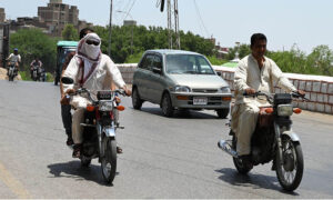 Motorcyclist covers his face with a handkerchief to protect from scorching heat at Hilltop Road during hot weather in the city
