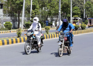 Motorcyclists cover their faces with piece of cloth to protect from scorching heat at University Road.