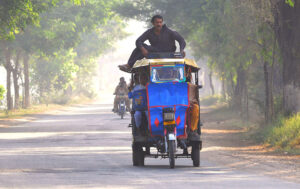 A person traveling on the roof of a motor rickshaw in a risky way may cause any mishap.