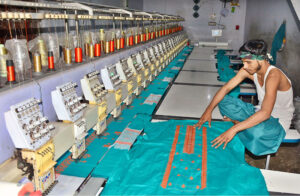 Worker busy in preparing the design on the fabric with help by machine at local textile factory.
