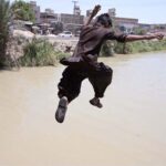 Youngsters jumping and bathing in the canal to get relief from hot weather in the city