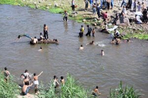 Youngsters jumping and bathing in nullah korang to get relief from scorching hot weather in Federal Capital.