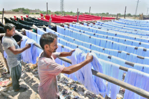 Worker busy in preparing the design on the fabric with help by machine at local textile factory.