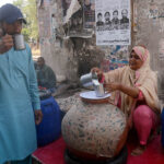 A Women Shopkeer drinking traditional summer drink (Lassi) from vendor to get relief from hot weather in the city