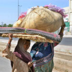 Labourers women on their way while carrying khas material on their heads to reach their destination.
