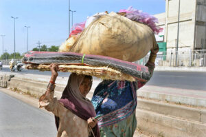 Labourers women on their way while carrying khas material on their heads to reach their destination.