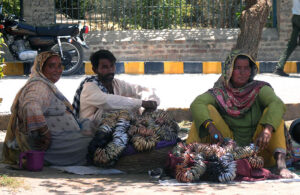 A vendor's family patiently waits for customers to buy bangles at their roadside setup.