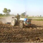 A farmer busy in preparing land for rice crop at Jhang Road with help of tractor