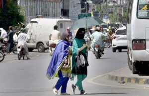 Women on their way under cover of an umbrella to protect from direct sunlight during scorching hot weather in the city.