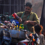 A vendor preparing traditional ice gola to attract customers at roadside during scorching hot weather in the city
