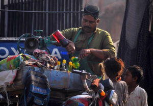 A vendor preparing traditional ice gola to attract customers at roadside during scorching hot weather in the city