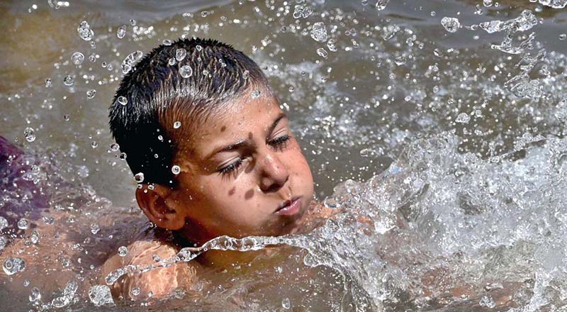 A youngster enjoy swimming in canal to get some relief from hot weather in Federal Capital.