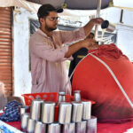 A vendor preparing traditional drink (Lassi) to attract customers during hot weather in the city