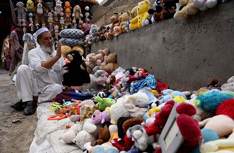 An old man is selling and displaying second hand imported toys to attract the customers at Kohati area.