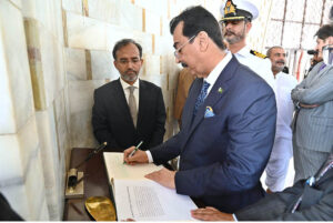 Acting President Syed Yousuf Raza Gillani pens down his remarks in the visitors' book at the Mausoleum of Quaid-e-Azam Muhammad Ali Jinnah.