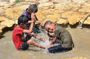 Children enjoying the bathing in the water to get relief from hot weather during heat wave.