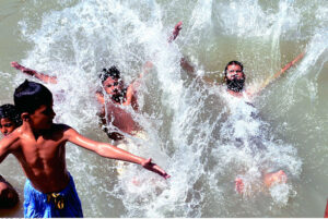 Youngsters jumping and bathing in water canal to get relief from hot weather in the city.