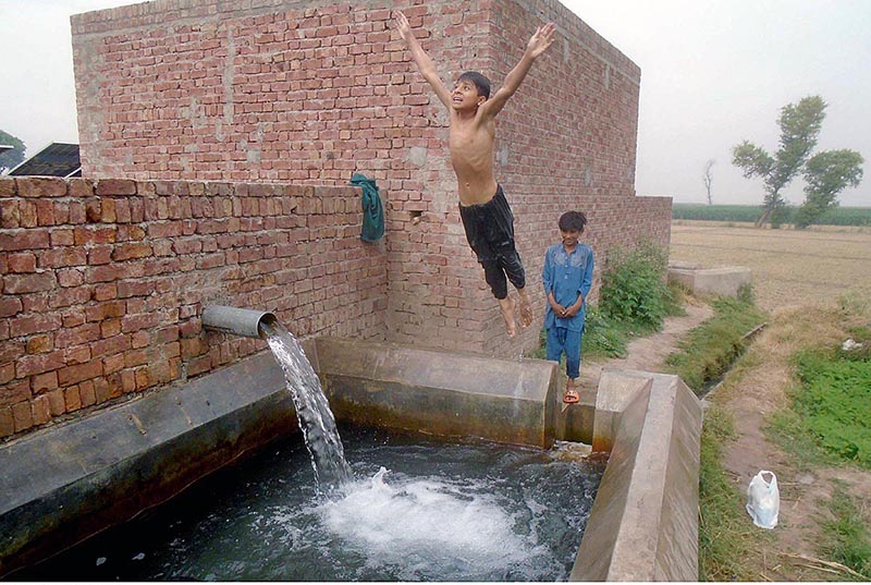 Youngsters bathing in tube well to get some relief from hot weather in the city