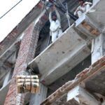 Laborers busy moving building material from the ground to the third floor using lift