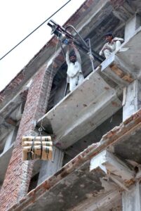 Laborers busy moving building material from the ground to the third floor using lift