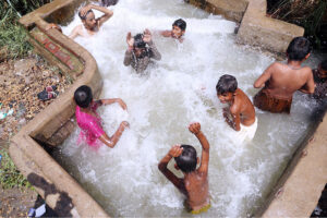 Children enjoying the bathing in the water to get relief from hot weather during heat wave.
