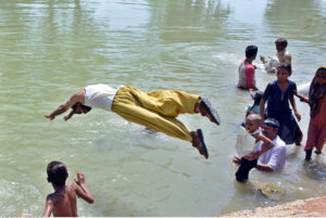 Youngsters jumping and bathing in water canal to get relief from hot weather in the city.