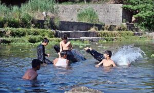 Youngsters jumping and bathing in Korang Nullah to get relief from hot weather in Federal Capital.
