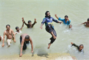 Youngsters jumping and bathing in water canal to get relief from hot weather in the city.